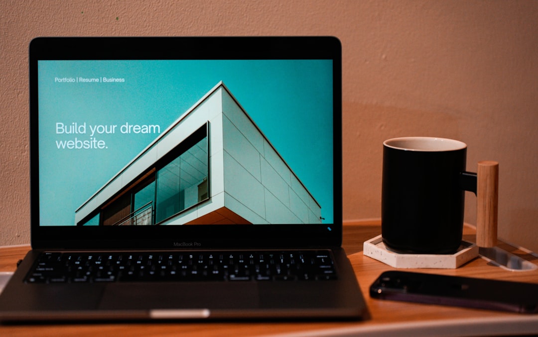 Créez le site web de vos rêves pour préparer votre avenir. Un ordinateur portable MacBook posé sur une table d’appoint portable, avec une tasse de café ou de thé sur le côté.